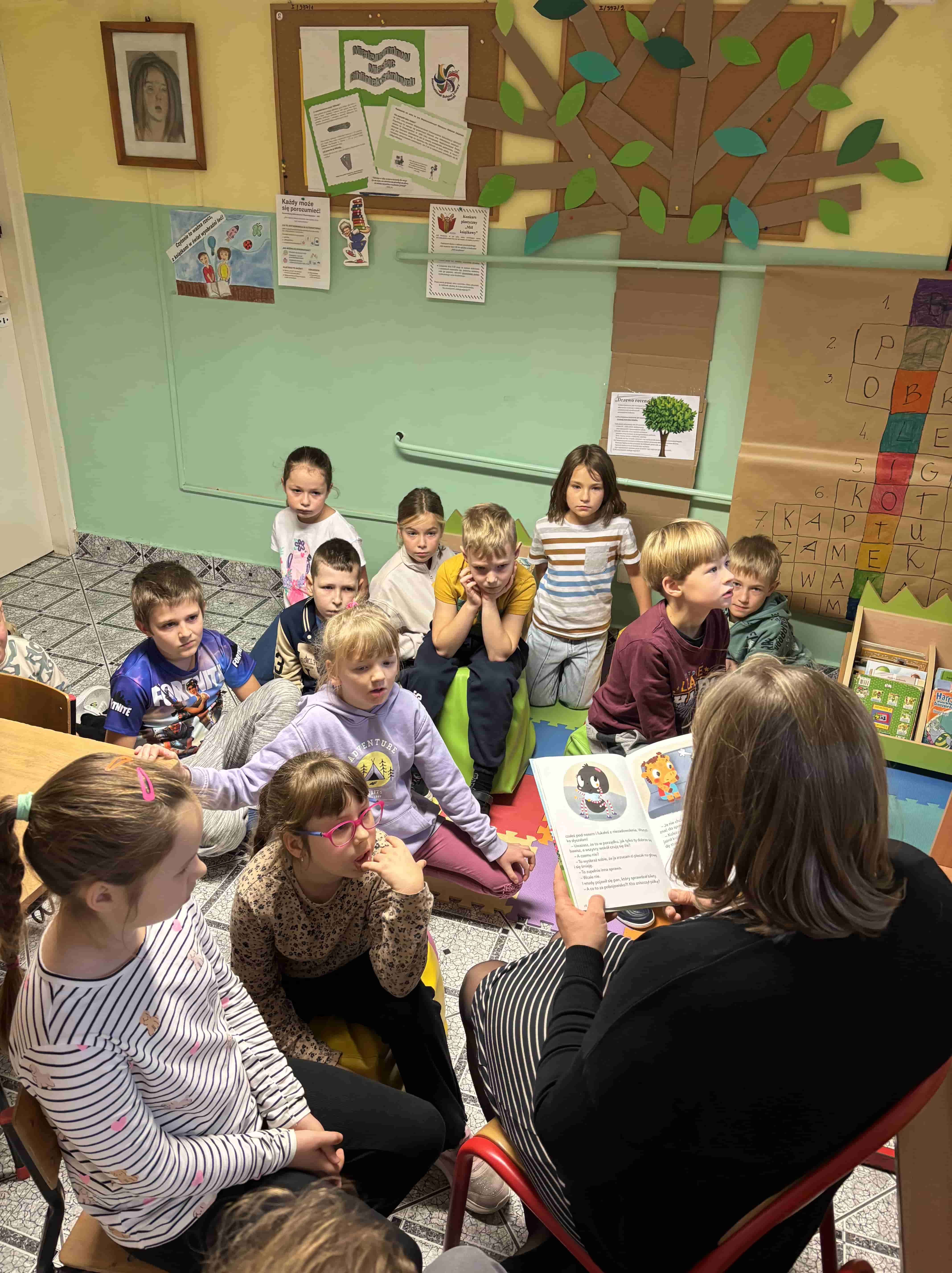 Pani bibliotekarka czyta dzieciom książkę w bibliotece