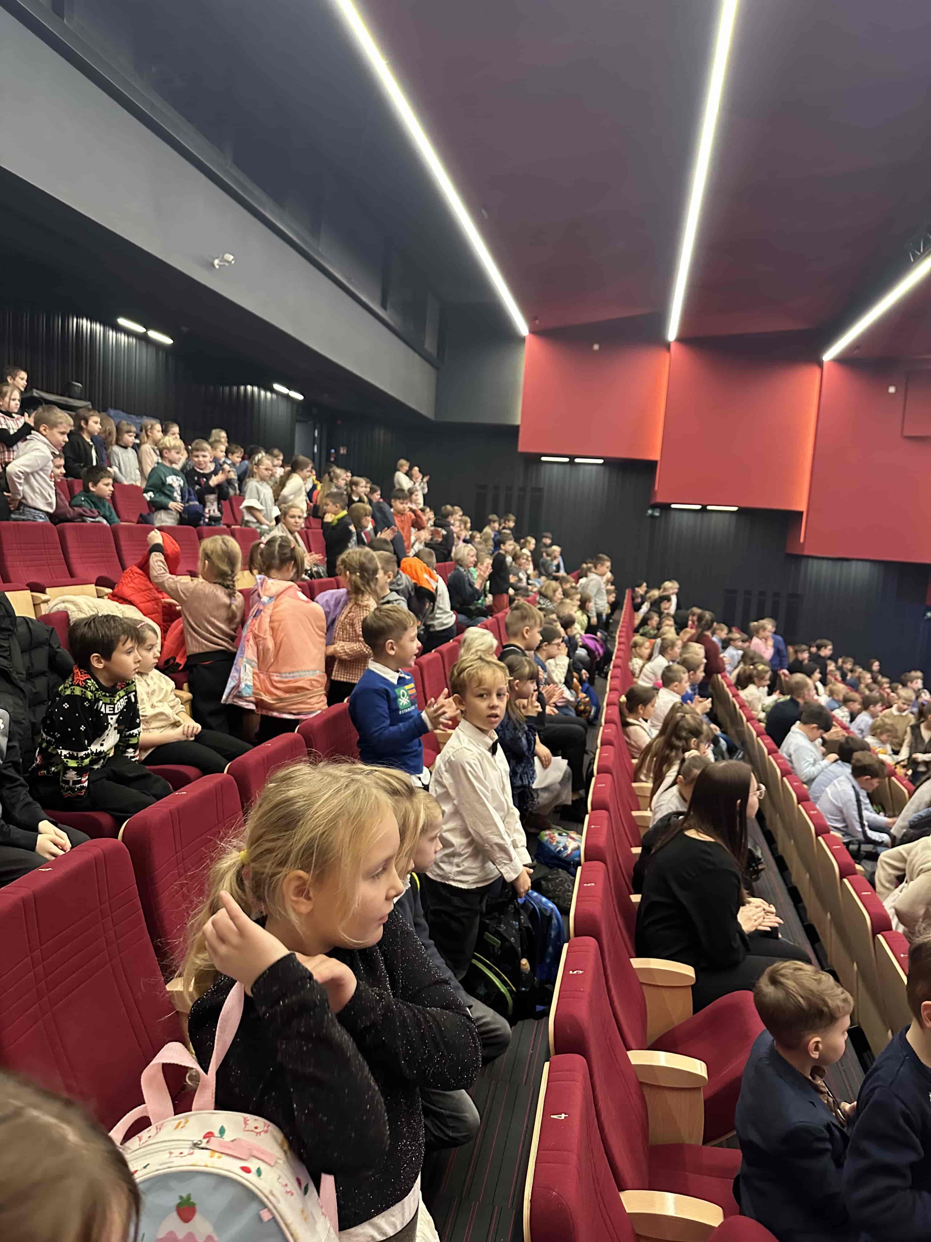 Uczniowie siedzący w sali teatralnej podczas spektaklu ‘Zaczarowany ołówek’