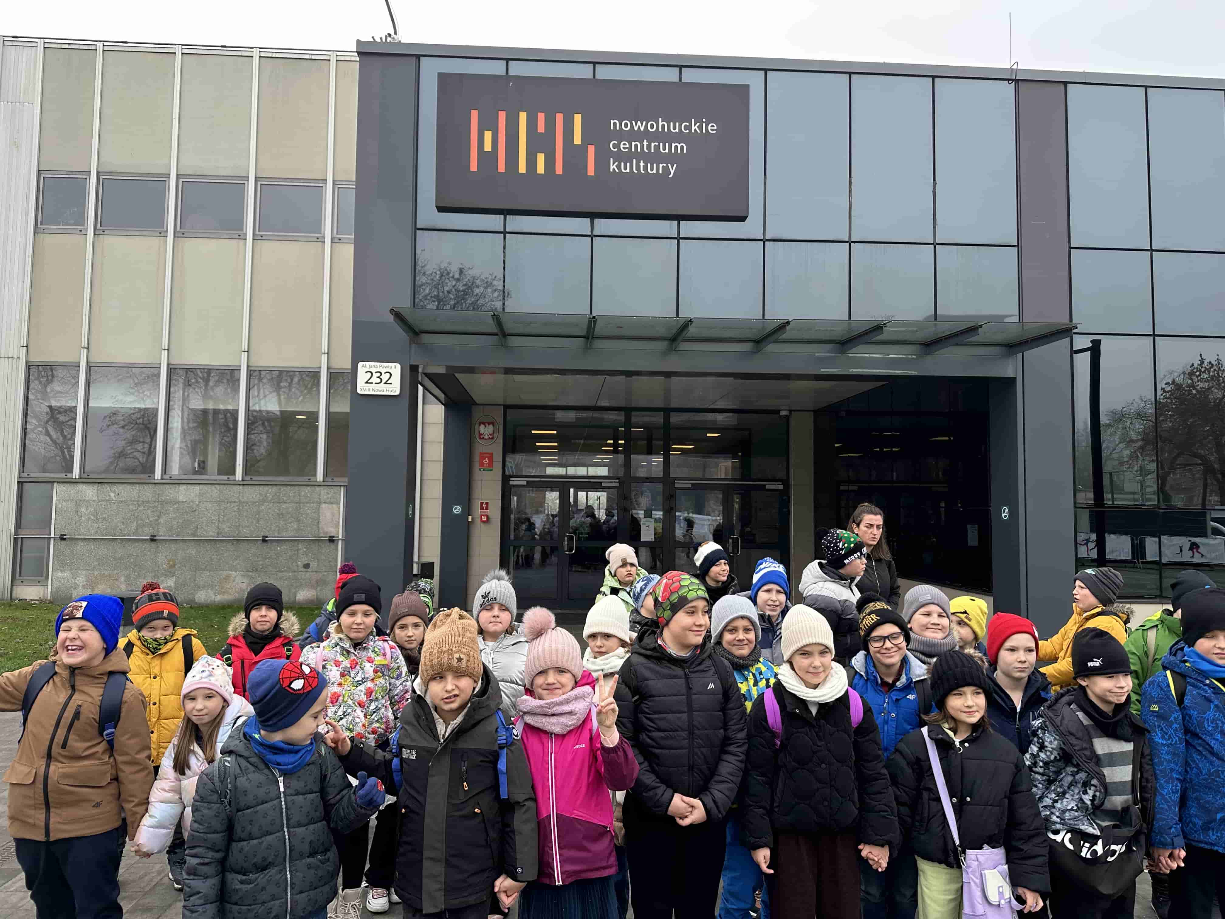Uczniowie stojący przed wejściem do Nowohuckiego Centrum Kultury w Krakowie