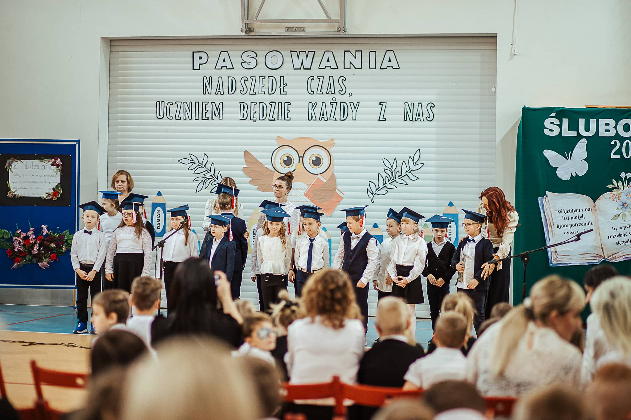 Grupa uczniów stojących na sali gimnastycznej podczas uroczystego ślubowania