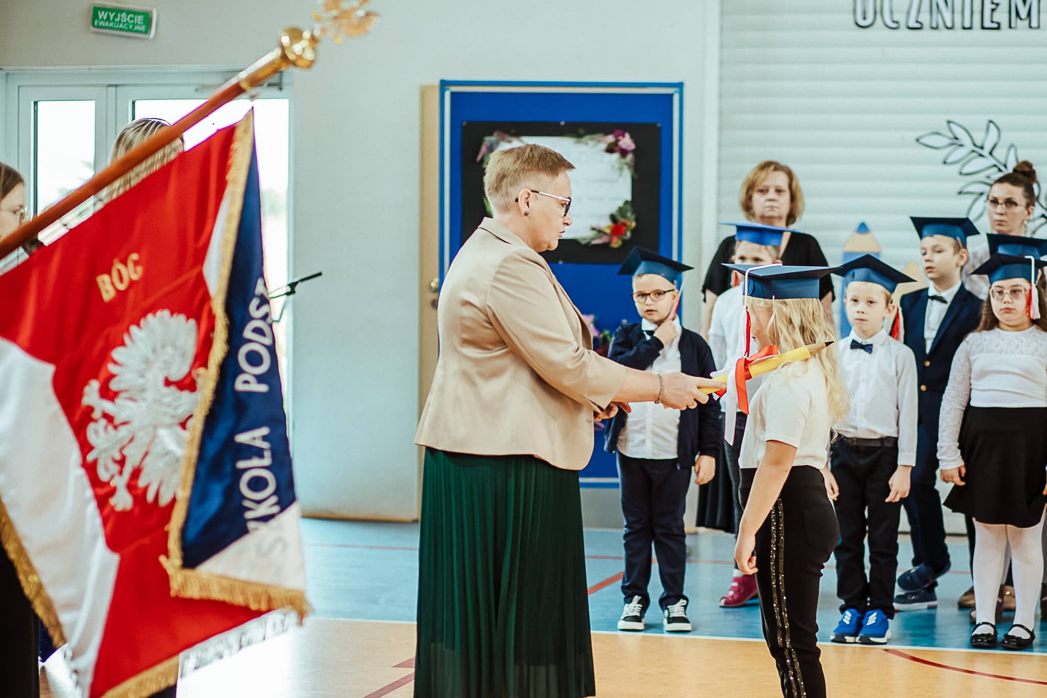 Pani Dyrektor dokonuje pasowania uczennicy podczas ceremonii ślubowania