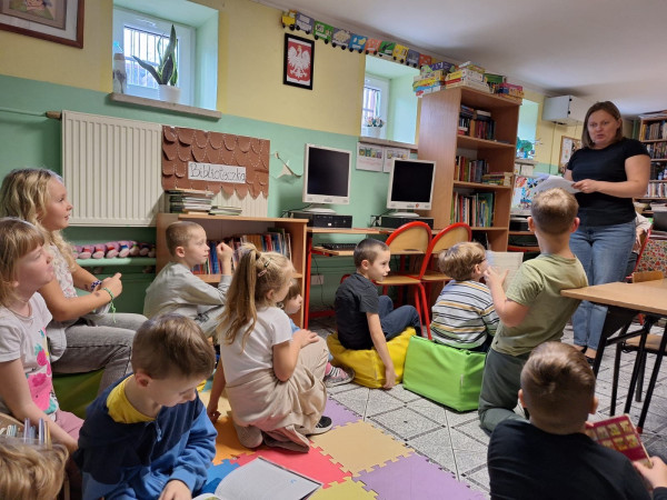Uczniowie siedzący w bibliotece i słuchający pani bibliotekarki, zdjęcie 3 z 5