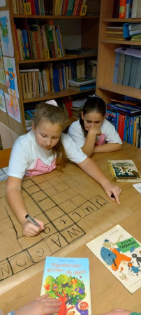 Grupa uczniów rozwiązuje krzyżówkę przy stoliku, zdjęcie 1 z 4