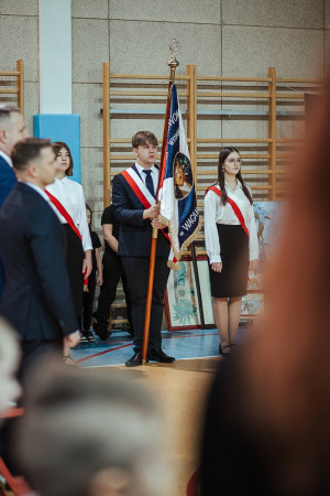 Uczniowie pocztu sztandarowego stoją w szeregu, prezentując sztandar podczas uroczystości, zdjęcie 1 z 10