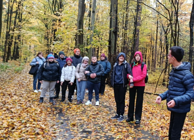 Grupa uczniów spaceruje leśną ścieżką w jesiennej scenerii Ojcowskiego Parku Narodowego, zdjęcie 2 z 3