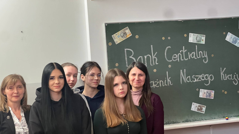 Uczniowie wraz z nauczycielami stoją przed tablicą z nazwą projektu dotyczącą banku centralnego— zdjęcie 1 z 5