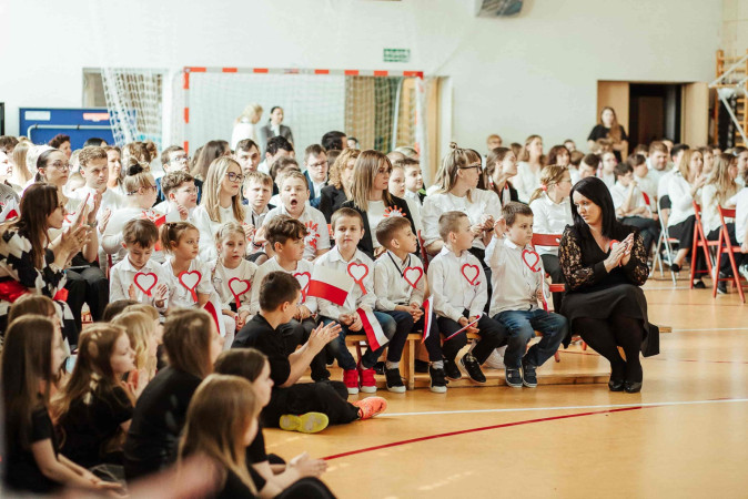 Uczniowie na widowni w strojach galowych z biało-czerwonymi sercami, zdjęcie 5 z 5