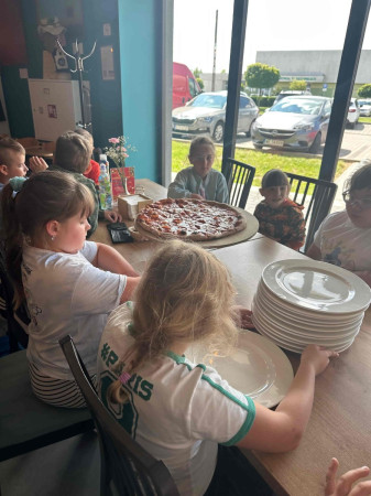 Uczniowie dzielą się porcjami pizzy w restauracji, zdjęcie 1 z 5