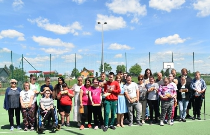 Uczniowie i seniorzy pozują do wspólnego zdjęcia grupowego na boisku sportowym, zdjęcie 2 z 5