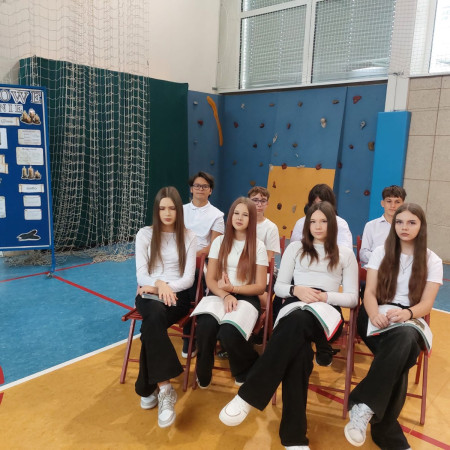 Uczniowie siedzą na krzesłach z książkami, zdjęcie 1 z 5