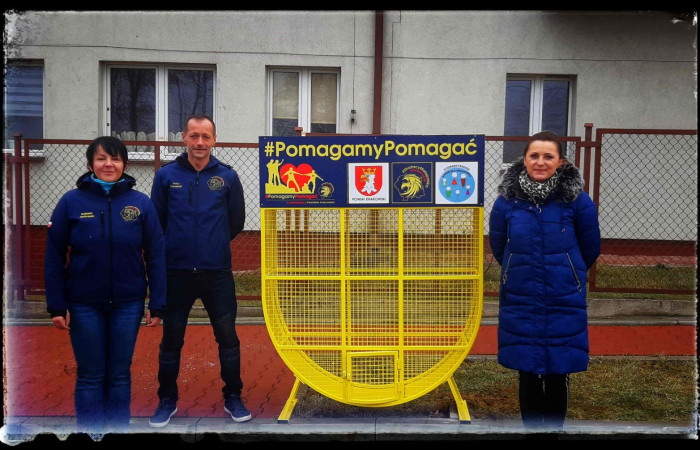 Organizatorzy akcji pozują przy pojemniku – symbolu pomocy i zaangażowania społecznego