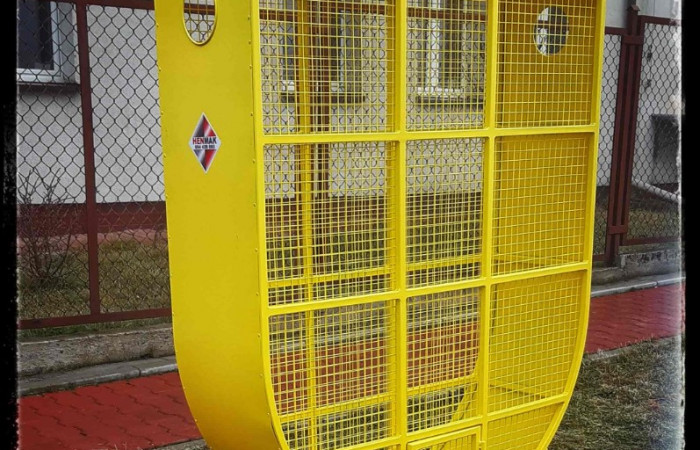 Żółty pojemnik na plastikowe zakrętki znajdujący się przy parkingu szkolnym